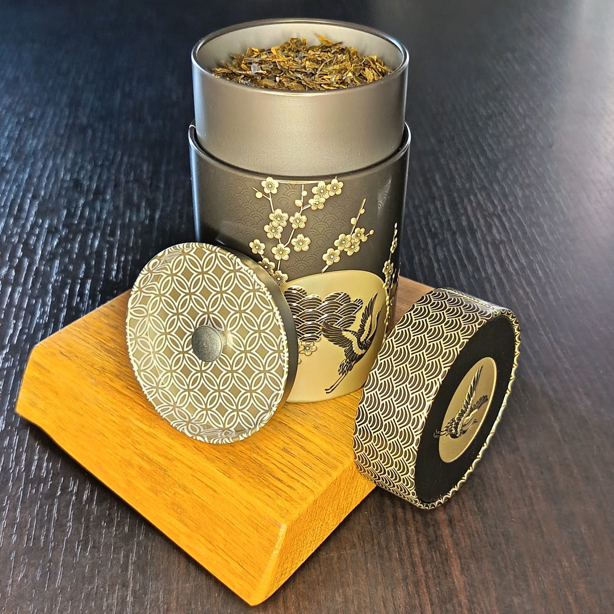Boîte à thé Komorebi noire ouverte, couvercle retiré et feuilles de thé en vrac — Teavora