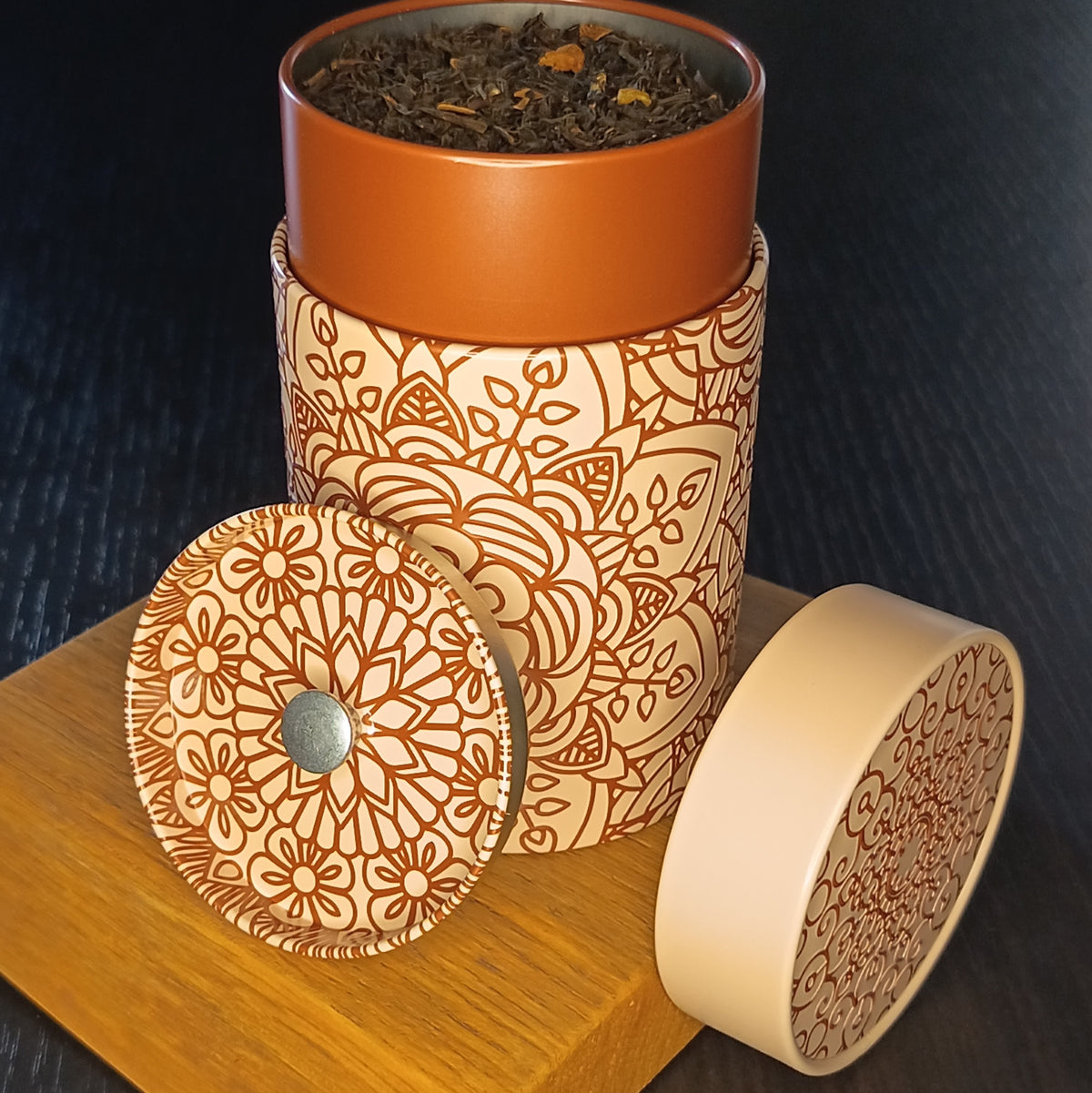 Boîte à thé Mandala beige ouverte, couvercle retiré et feuilles de thé en vrac — Teavora