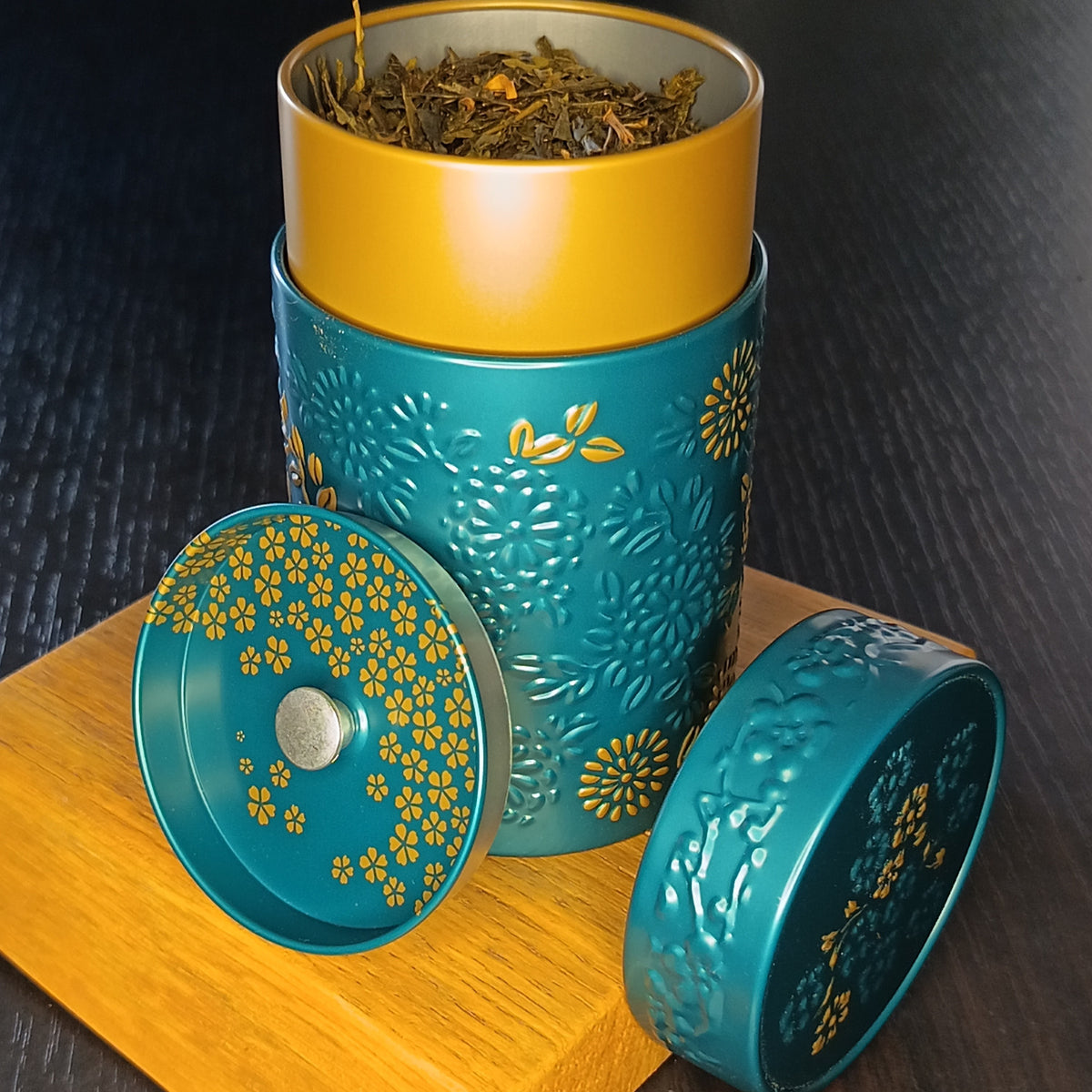 Boîte à thé Yumiko bleue ouverte, couvercle retiré et feuilles de thé en vrac — Teavora
