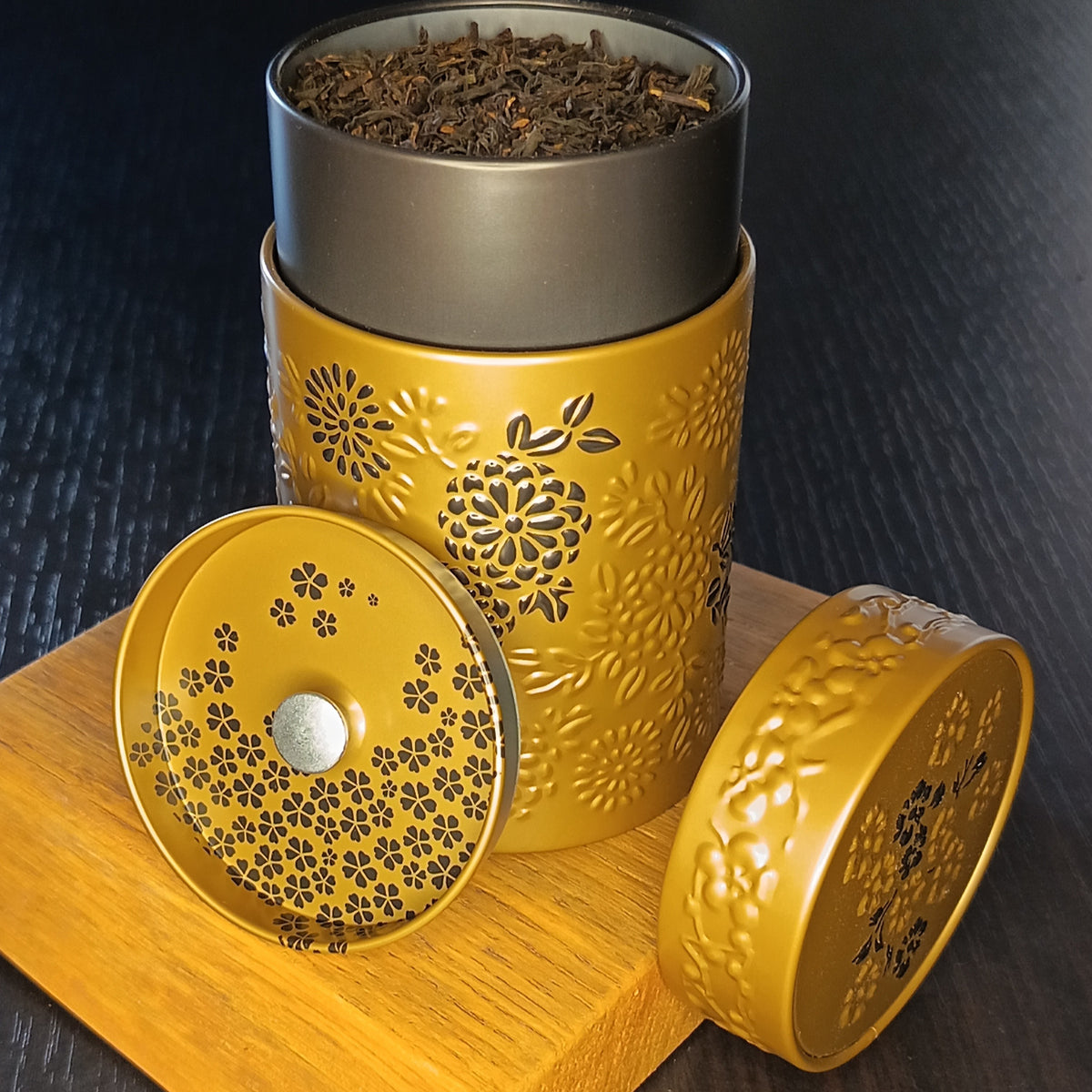 Boîte à thé Yumiko marron ouverte, couvercle retiré et feuilles de thé en vrac — Teavora