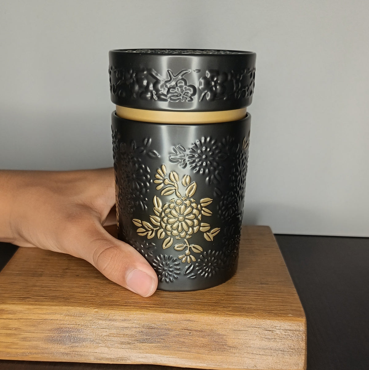 Boîte à thé en métal Yumiko noire 150 g tenue en main, taille réelle — Teavora